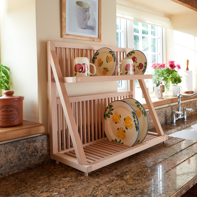 The countertop version of our plate storage rack, sat next to a sink on a kitchen worktop. Handmade from sustainably sourced beech wood, the plate rack is being used to store kitchen cups, saucers and other kitchenware items. 